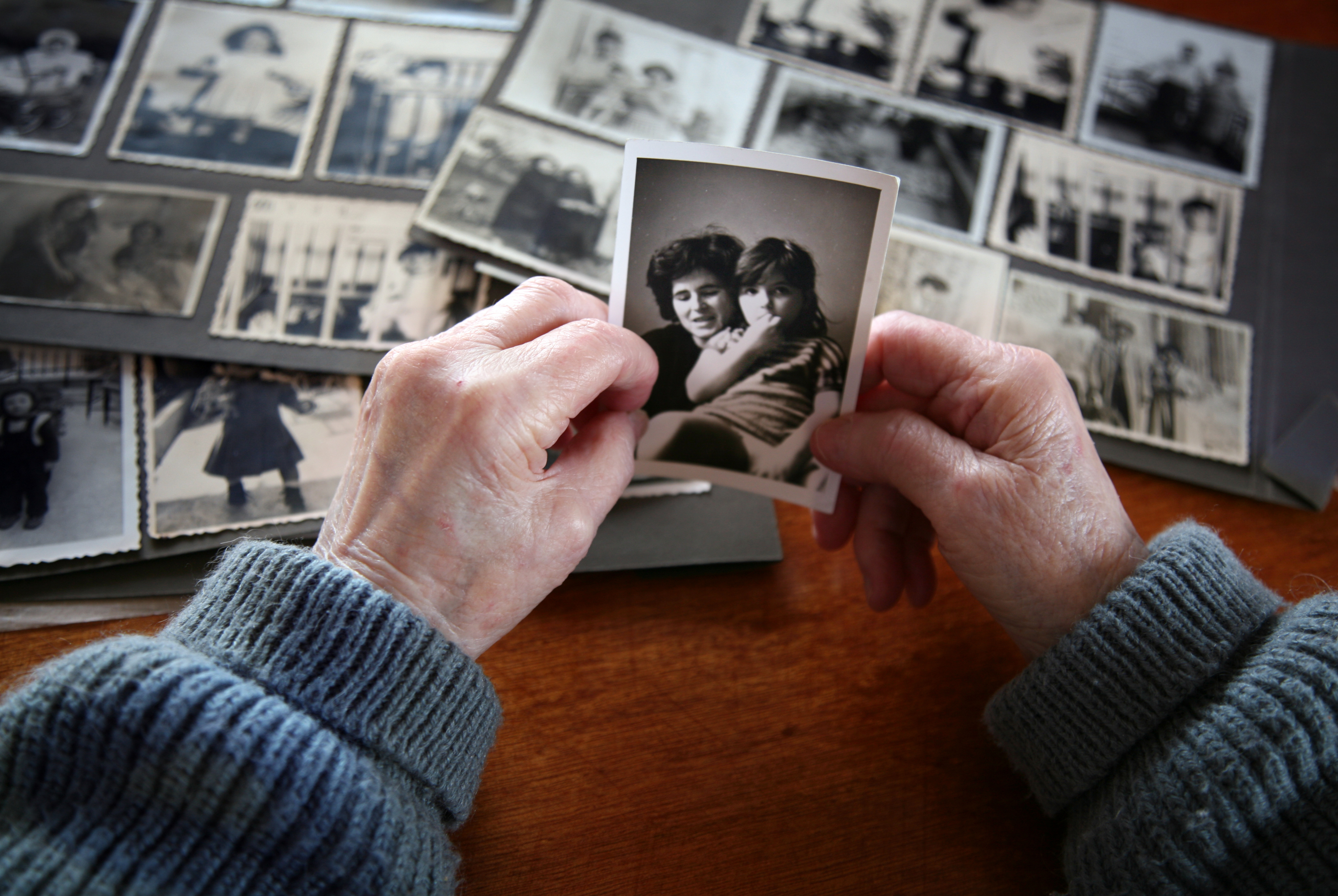 An elderly person's hands holding an old photo
