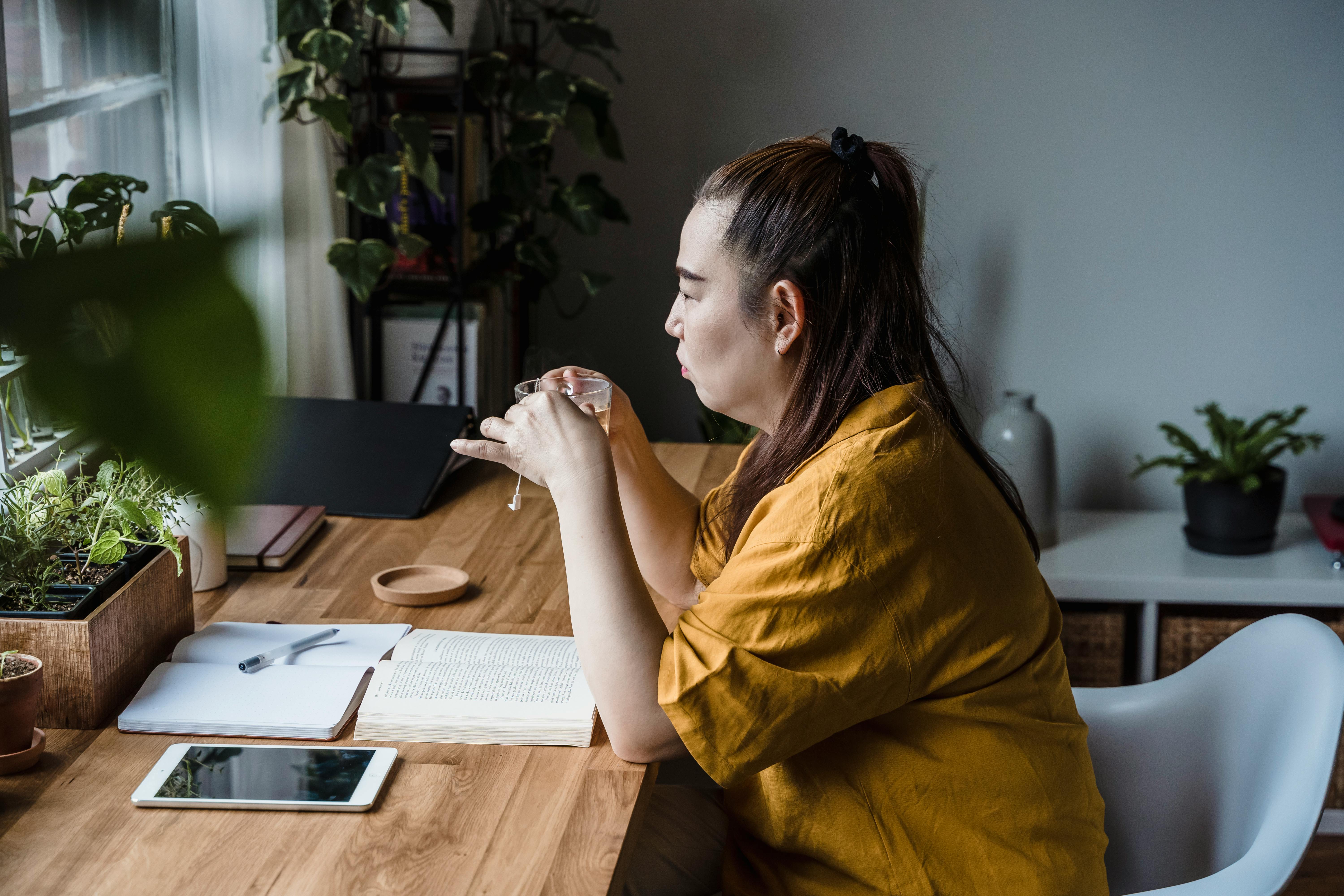 A woman holding a cup of tea at a desk