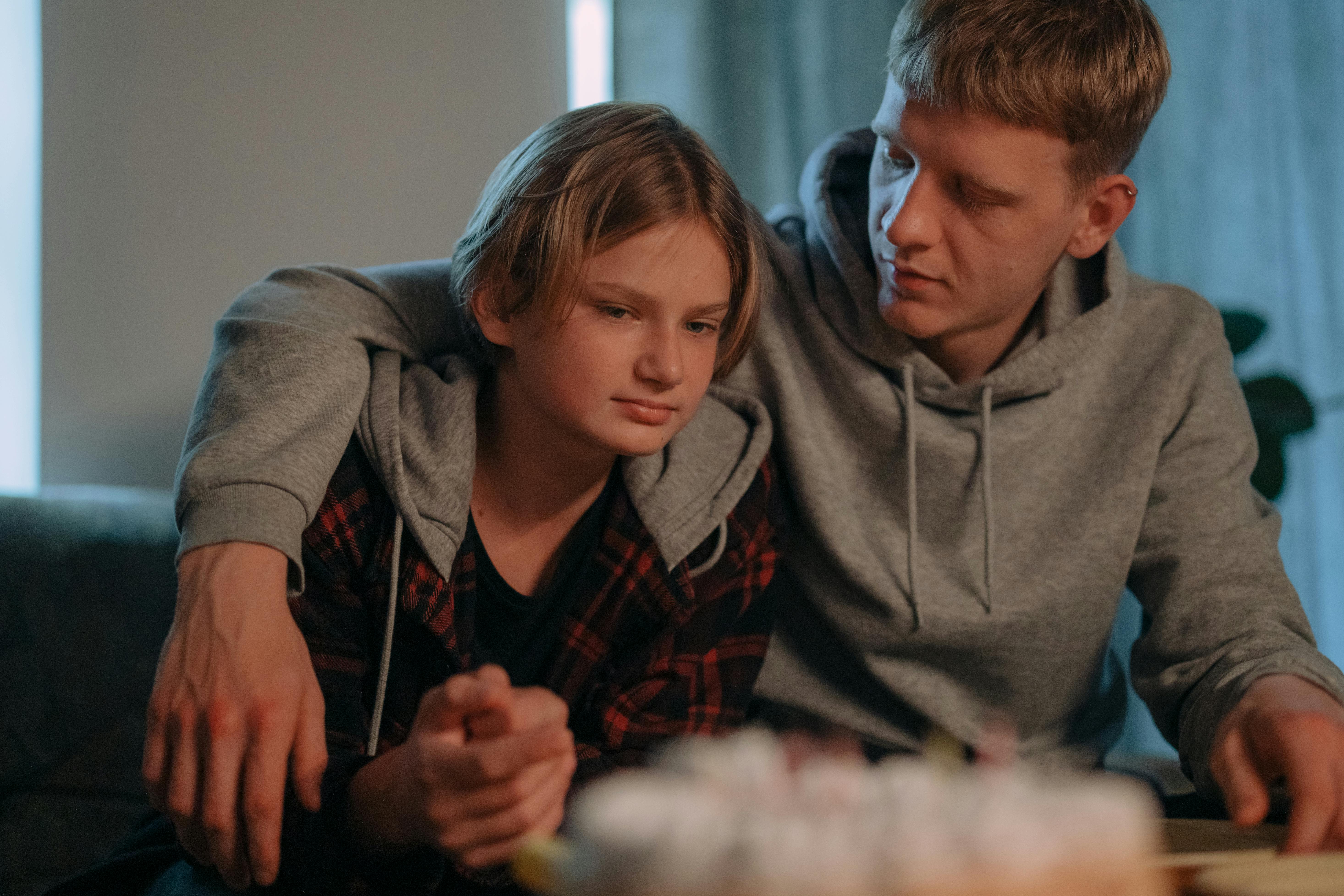 A man comforting a teenager