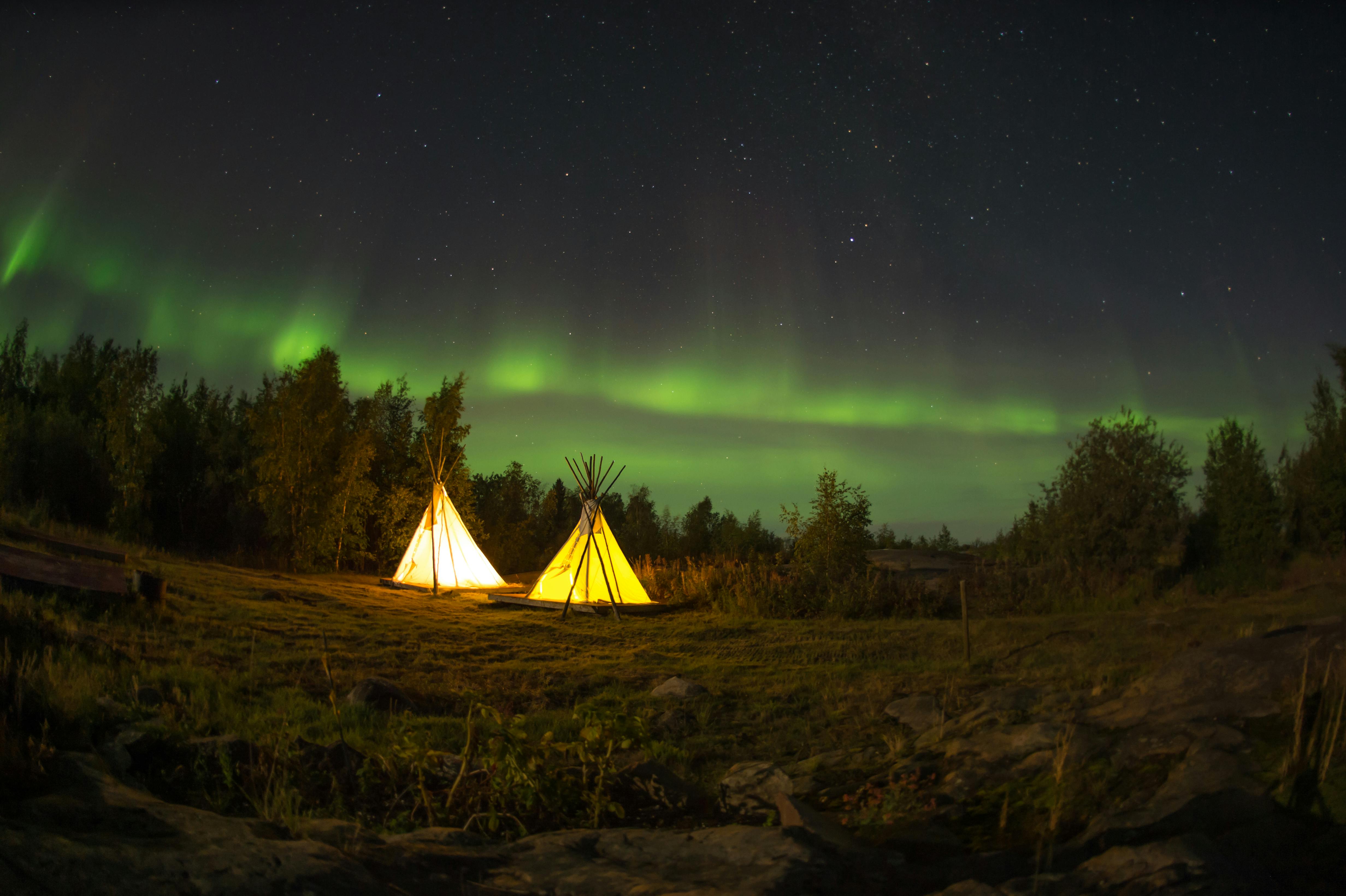 Tents on a green field under the northern lights