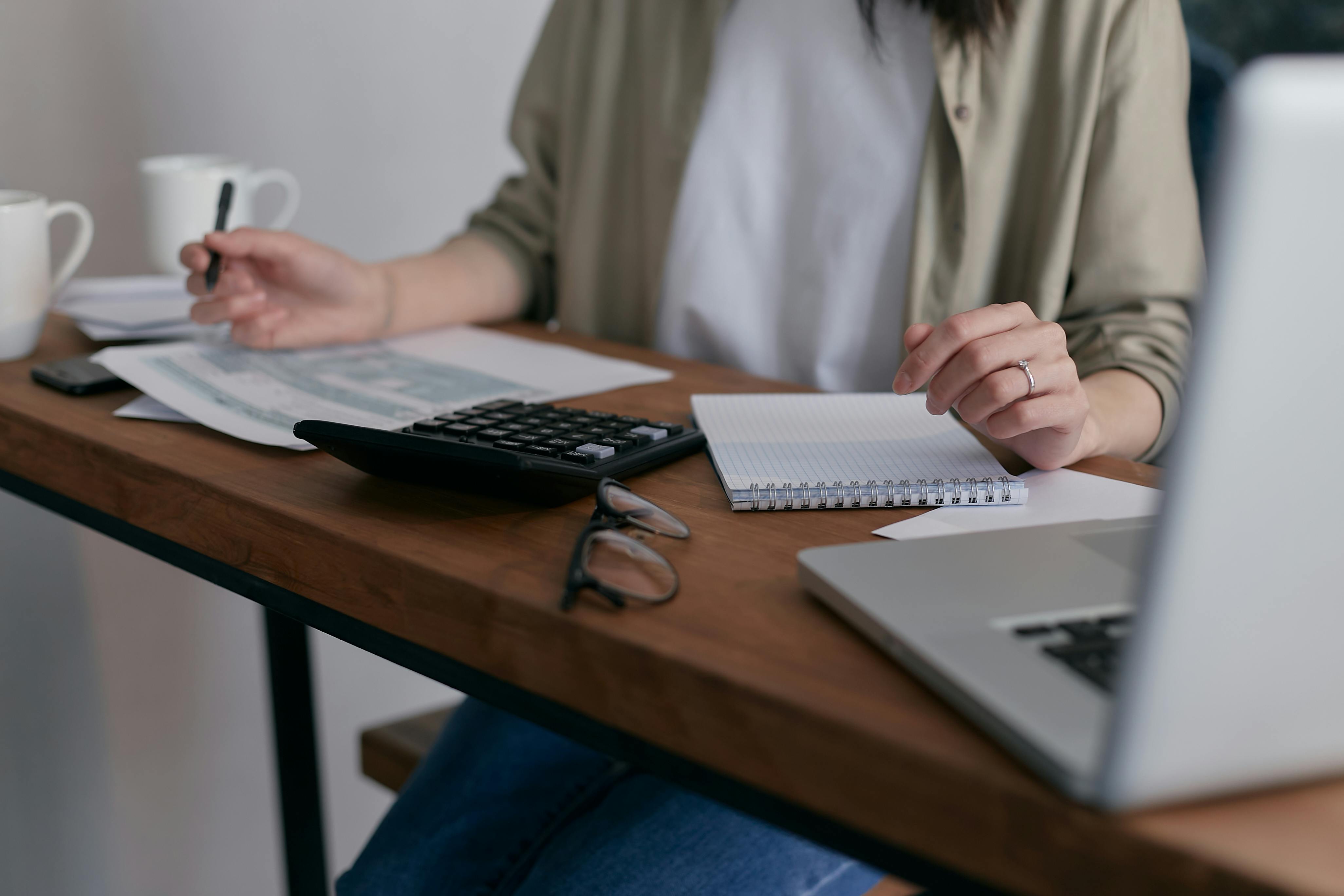A woman using a calculator and a laptop at a desk