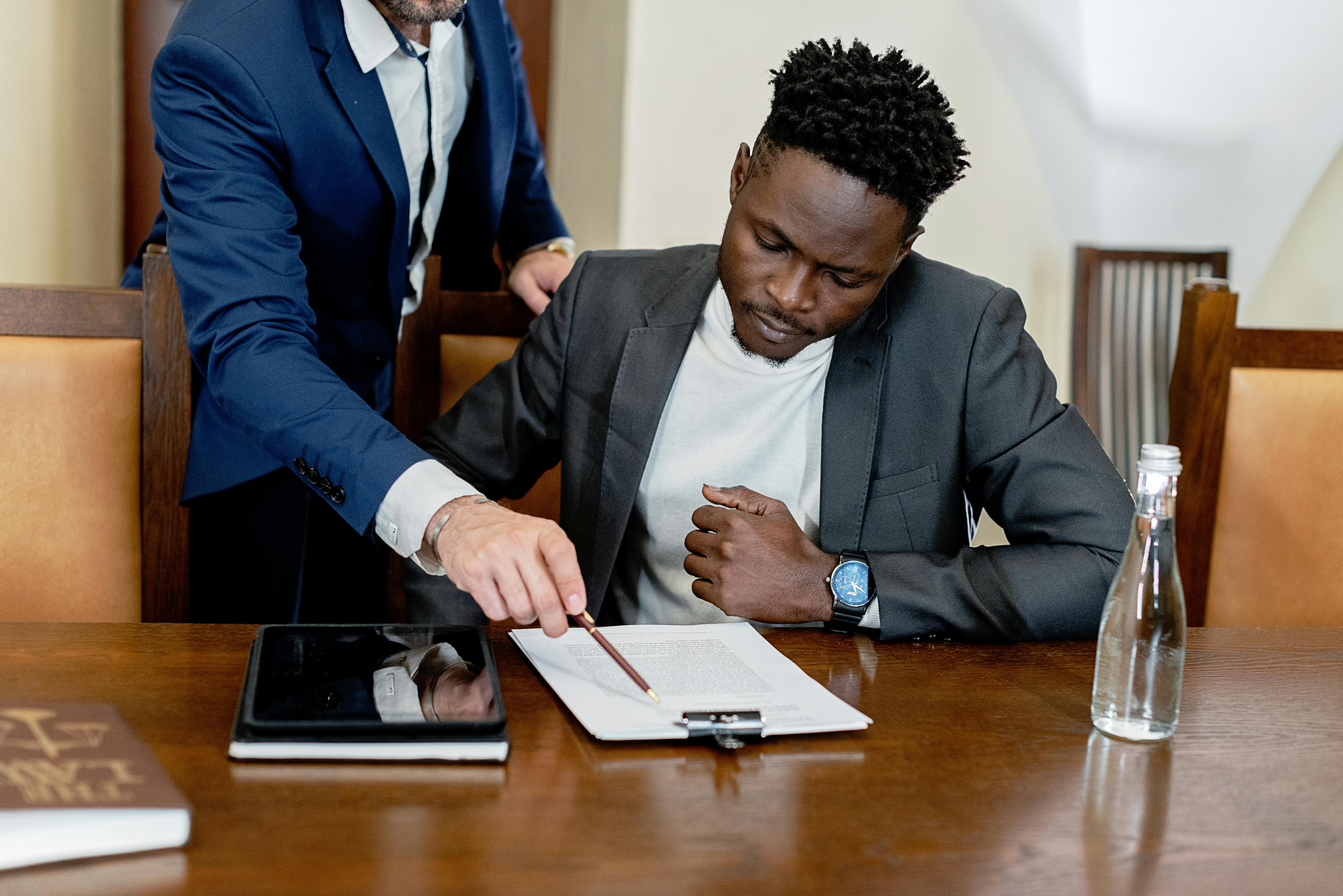 A Man in Gray Suit Looking at a Document on a Table