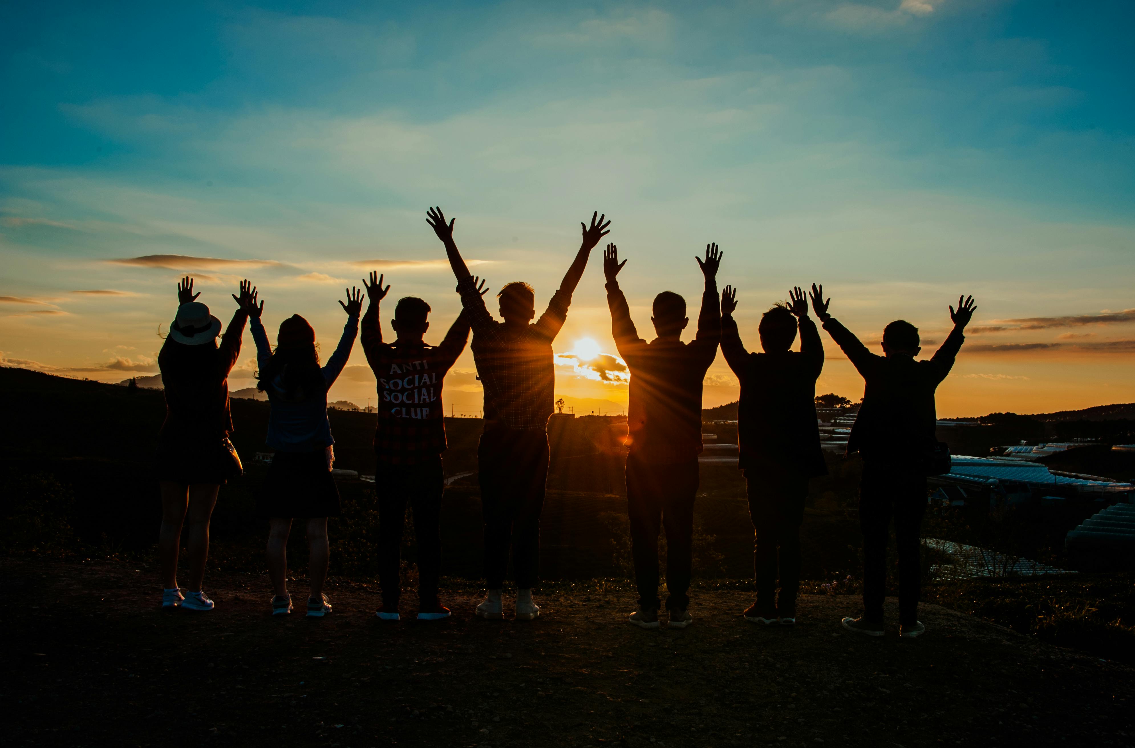 A photo of a group of people Silhouetted by a sunset