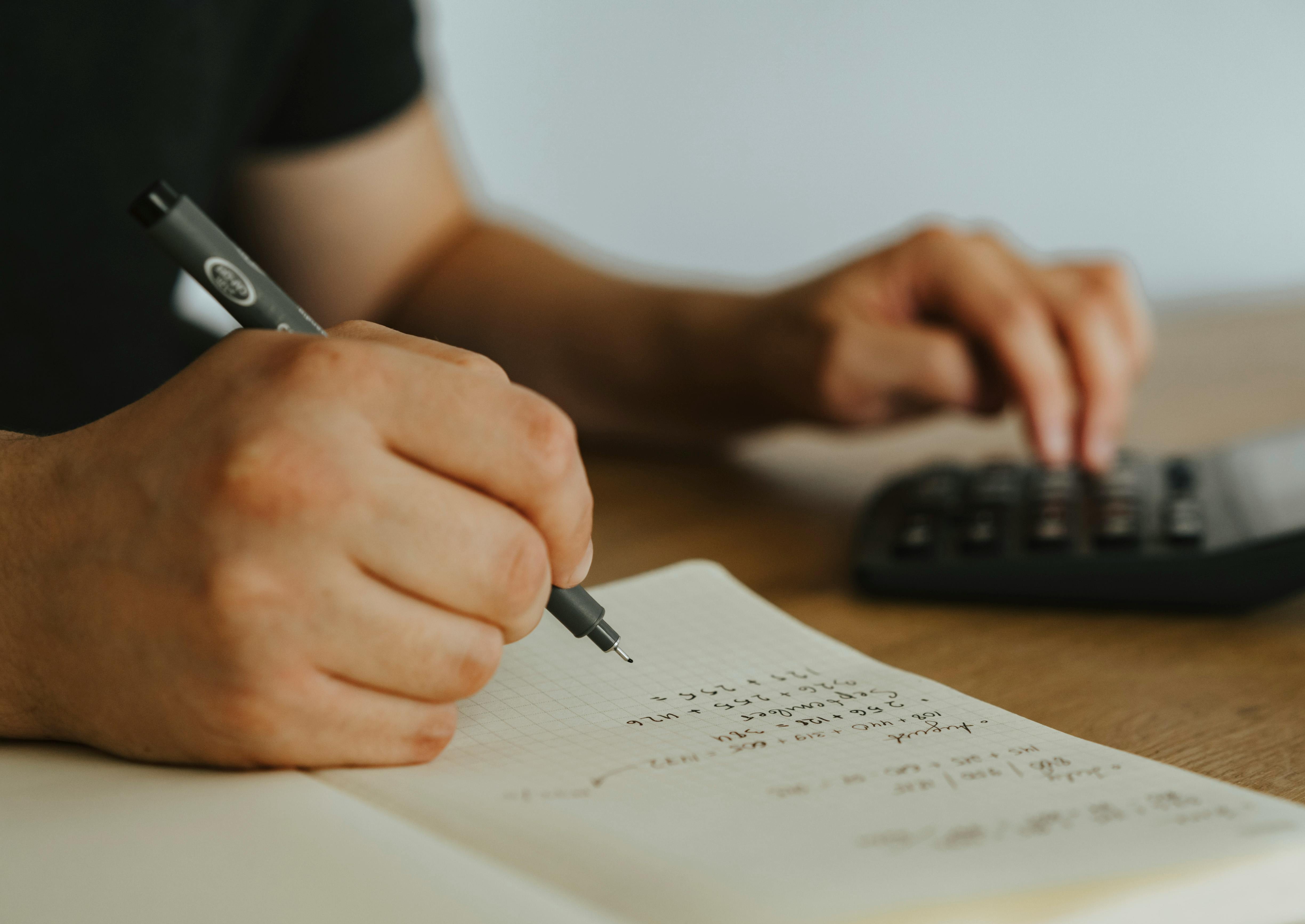 A person doing math with a notebook and calculator