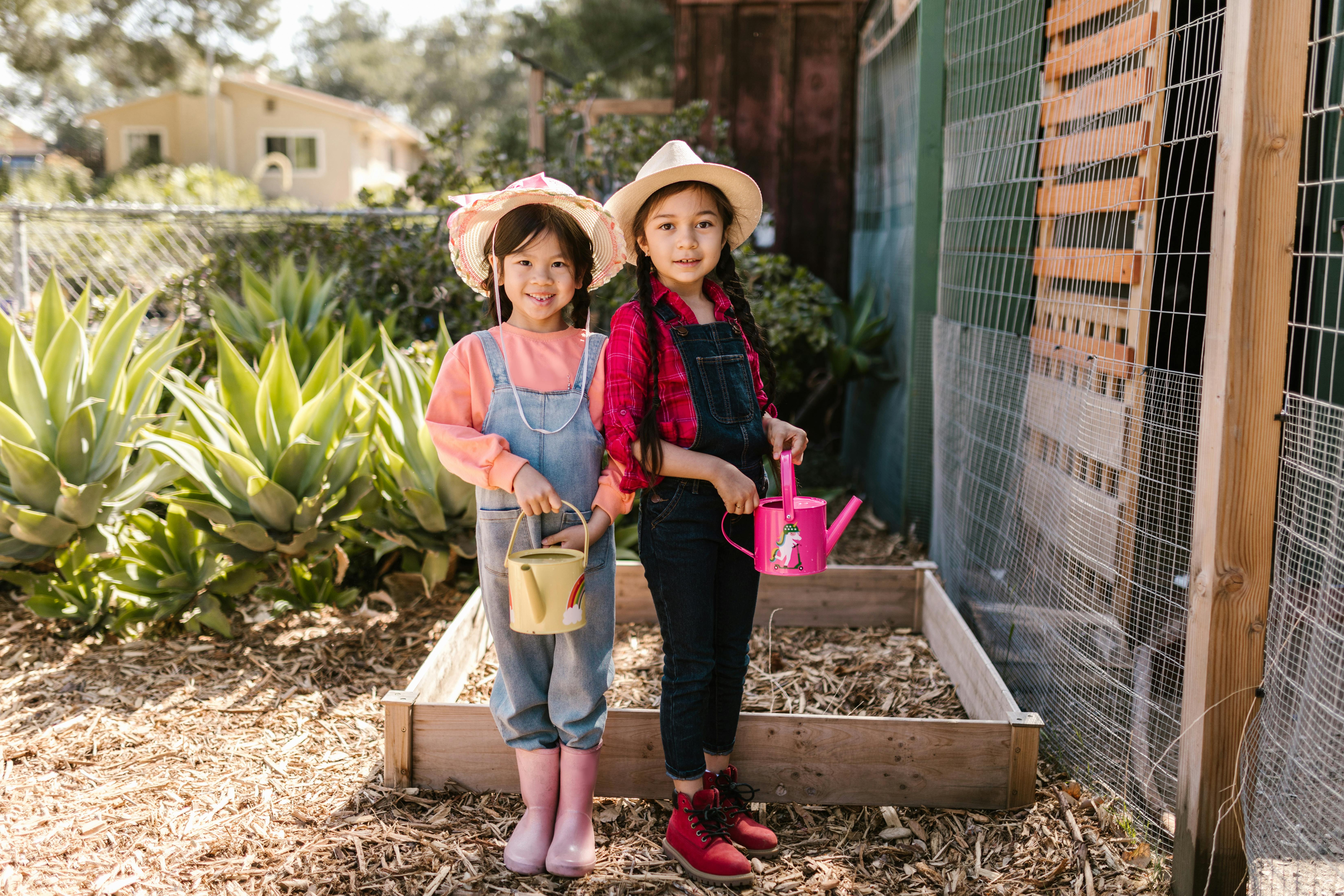 Two girls holding watering cans while gardening