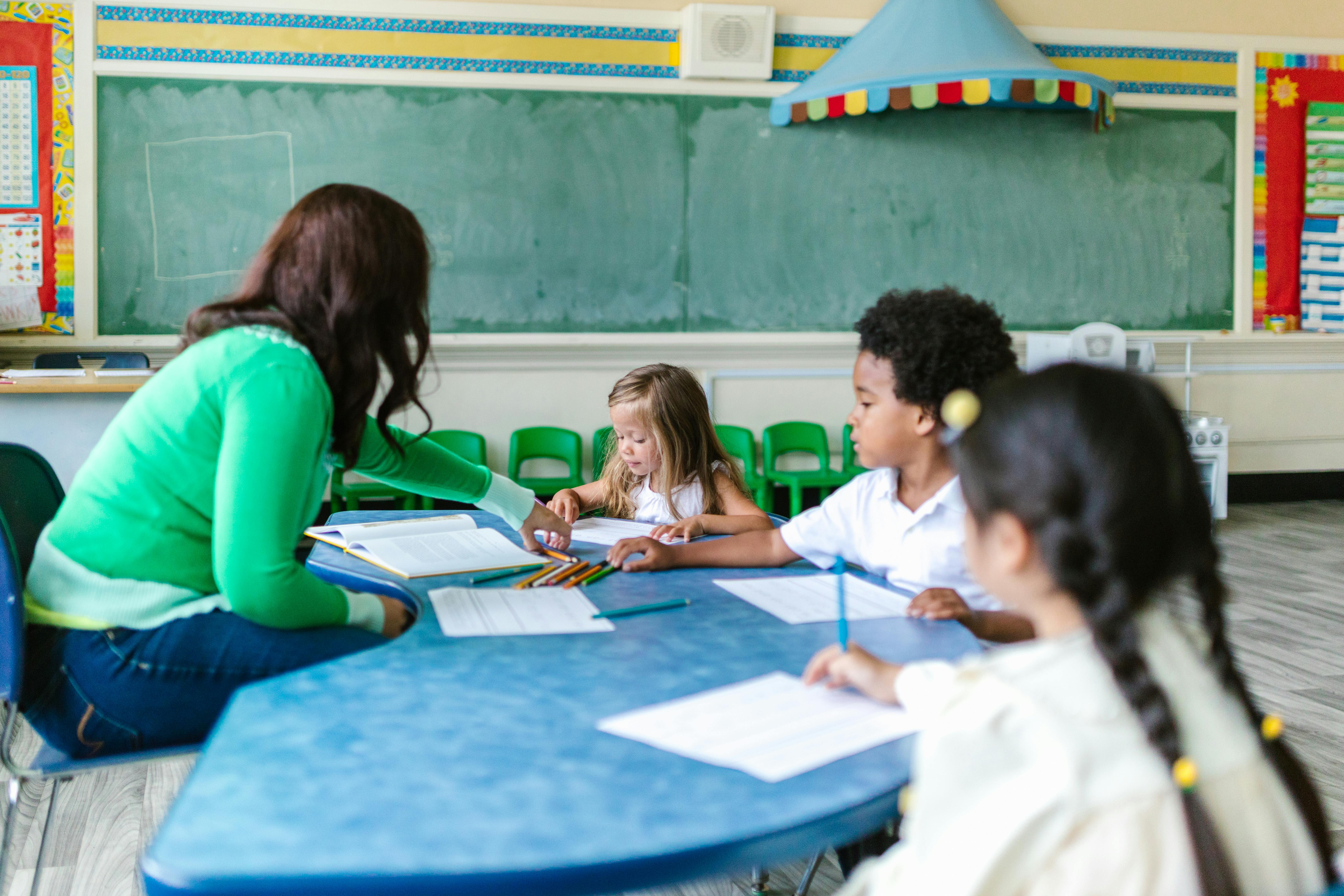 A teacher helping young students in a classroom