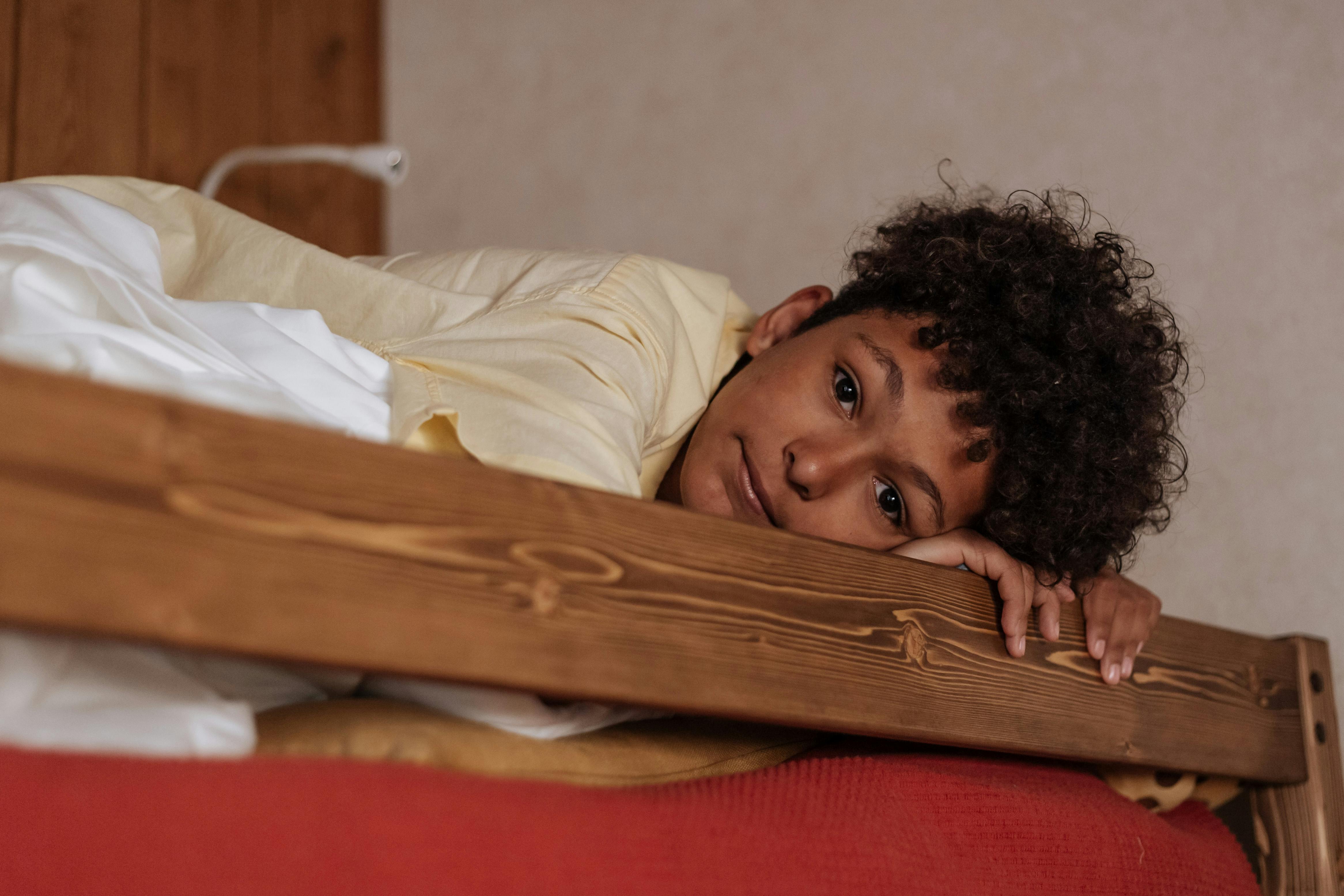 A boy looking down from a bunk bed