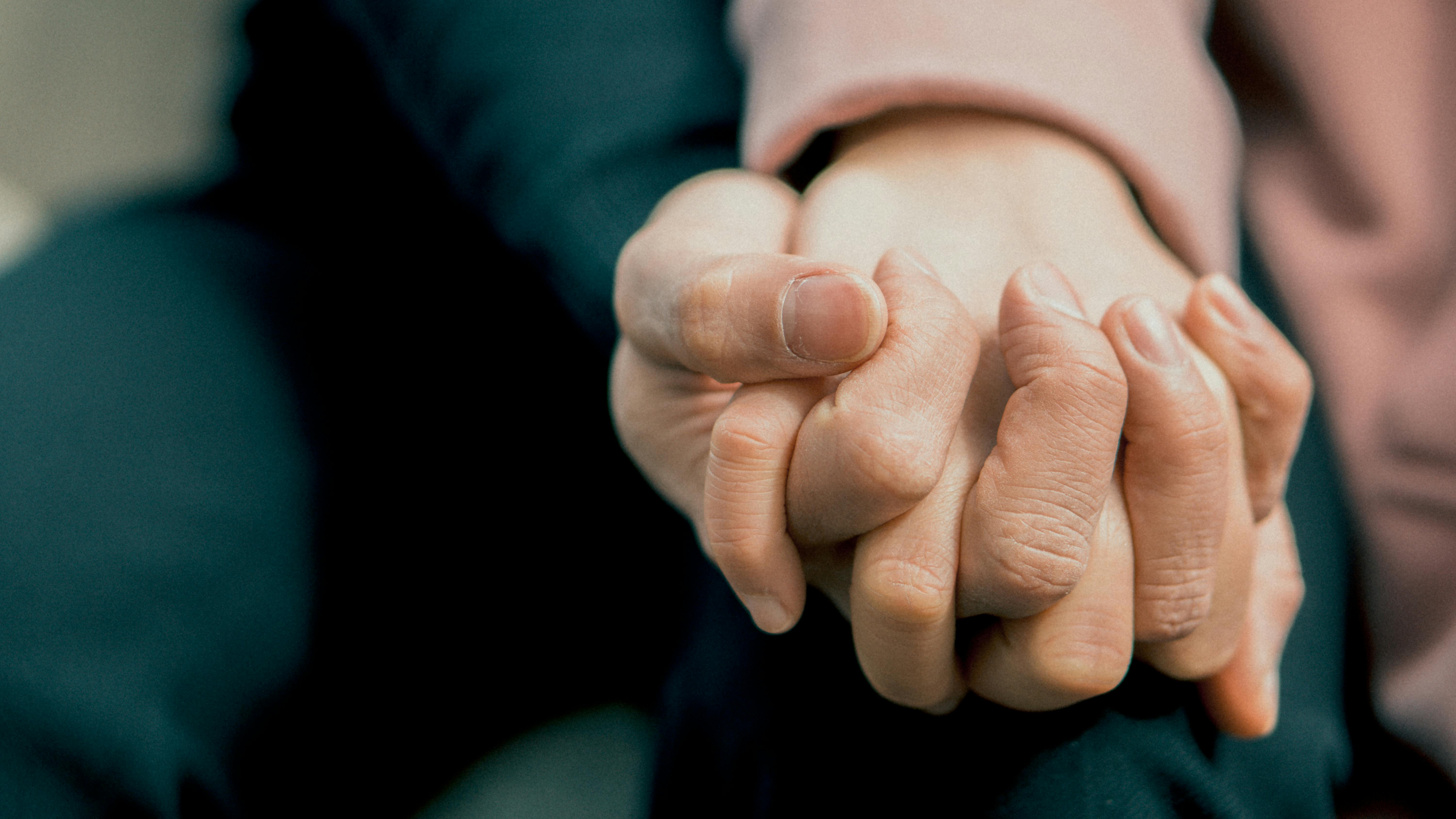Close up photo of two people holding hands