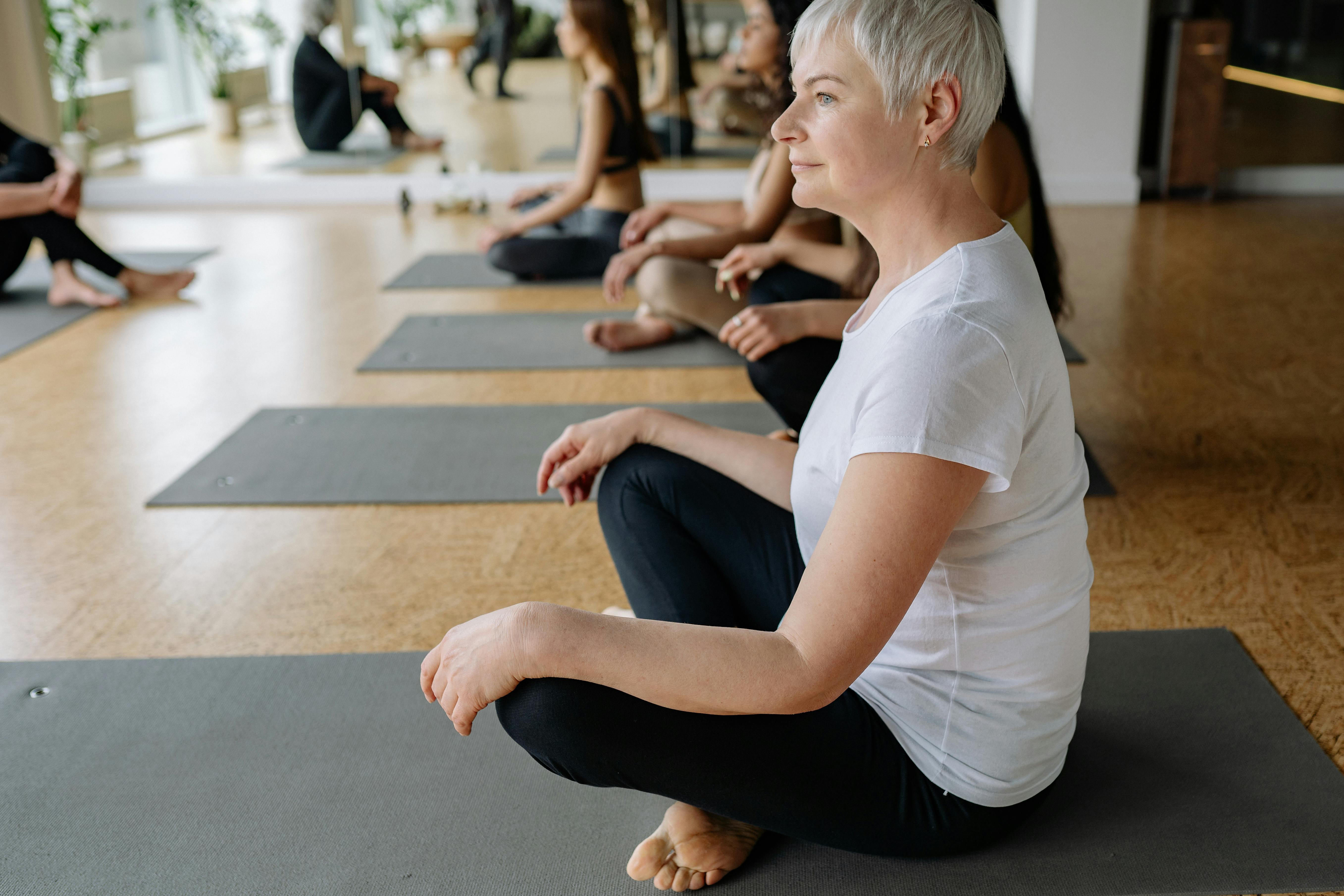 A senior woman practicing meditation a yoga class