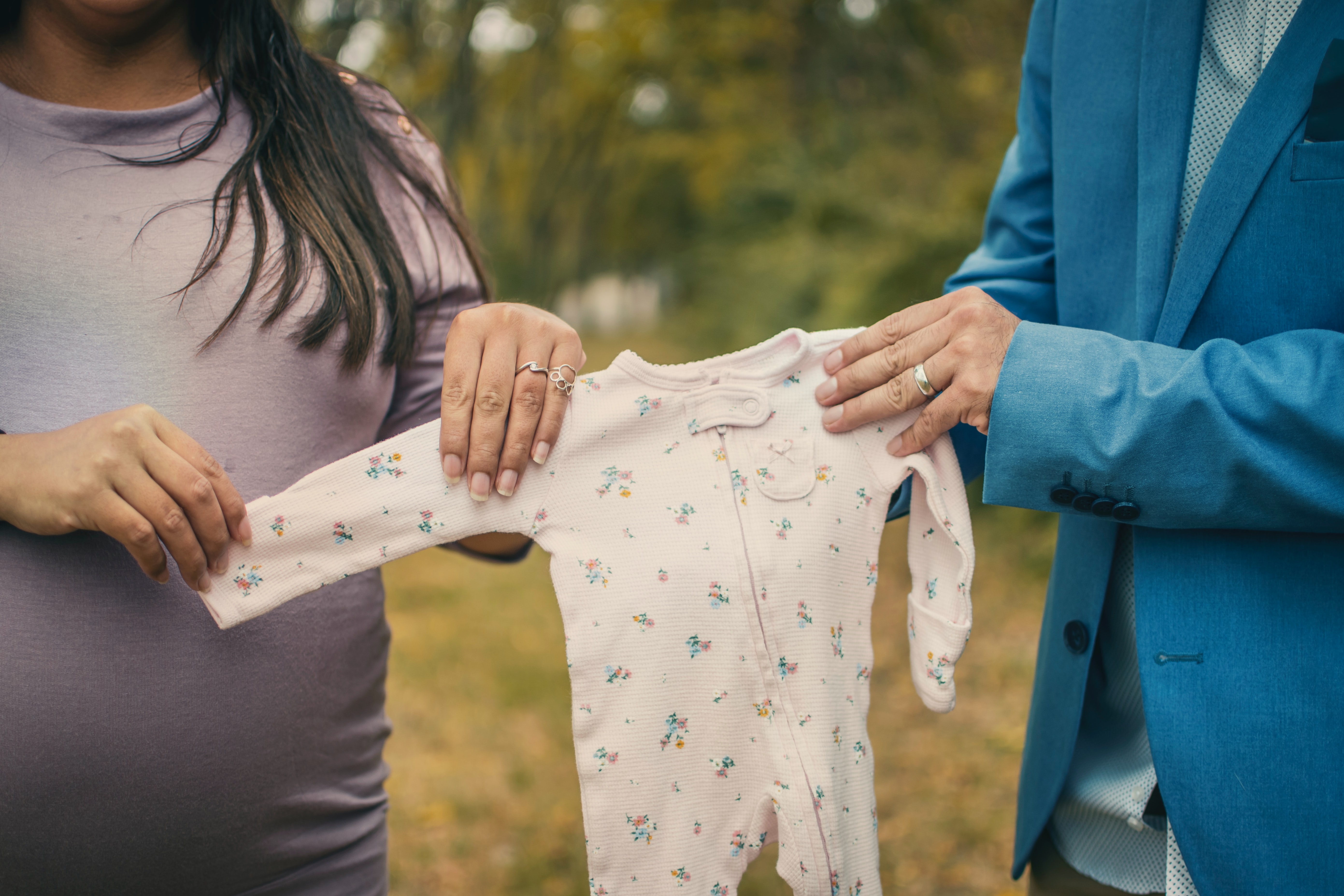 A man and a woman hold up a baby's onesie