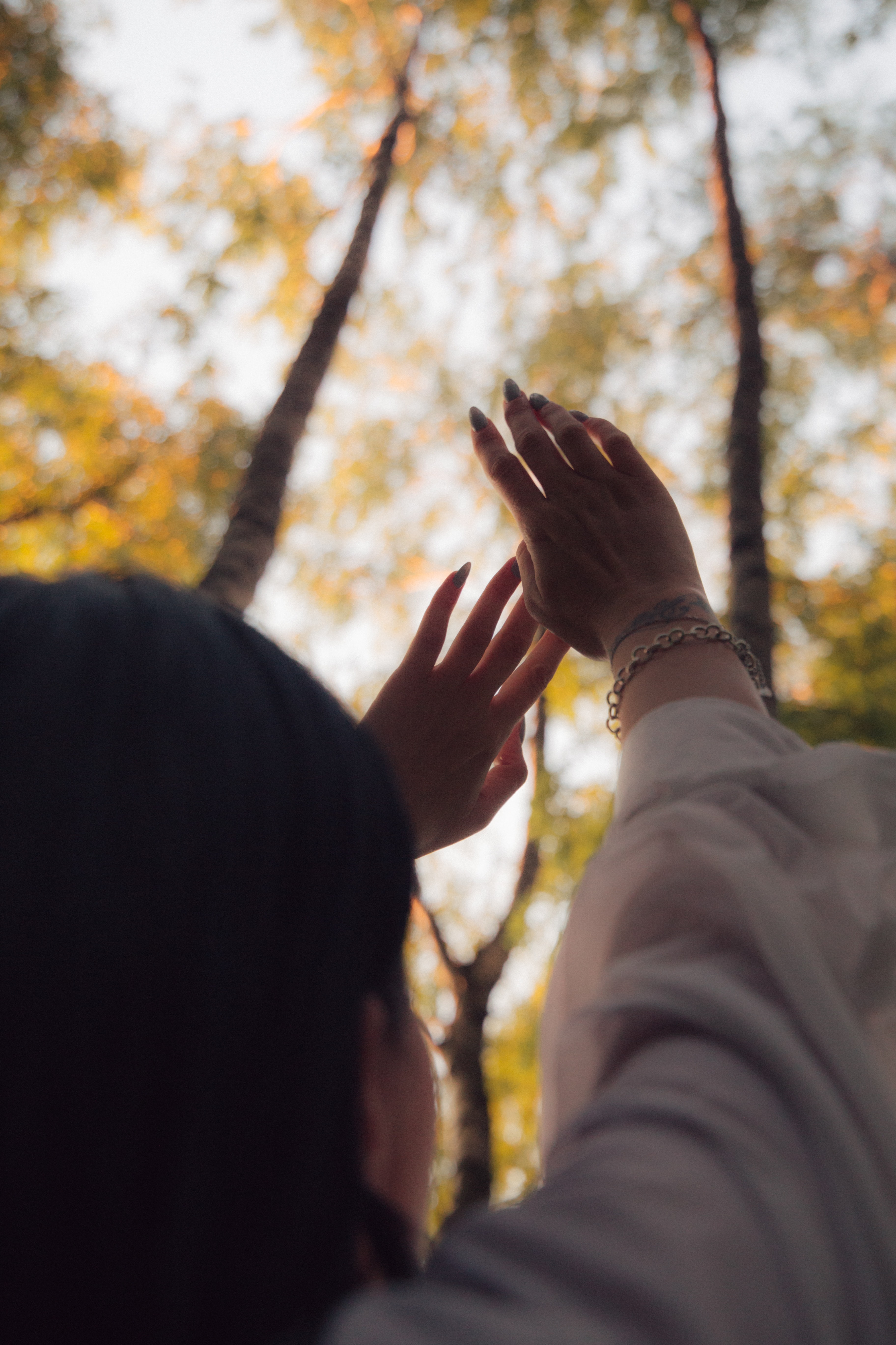 A woman holding her arms up under trees in autum