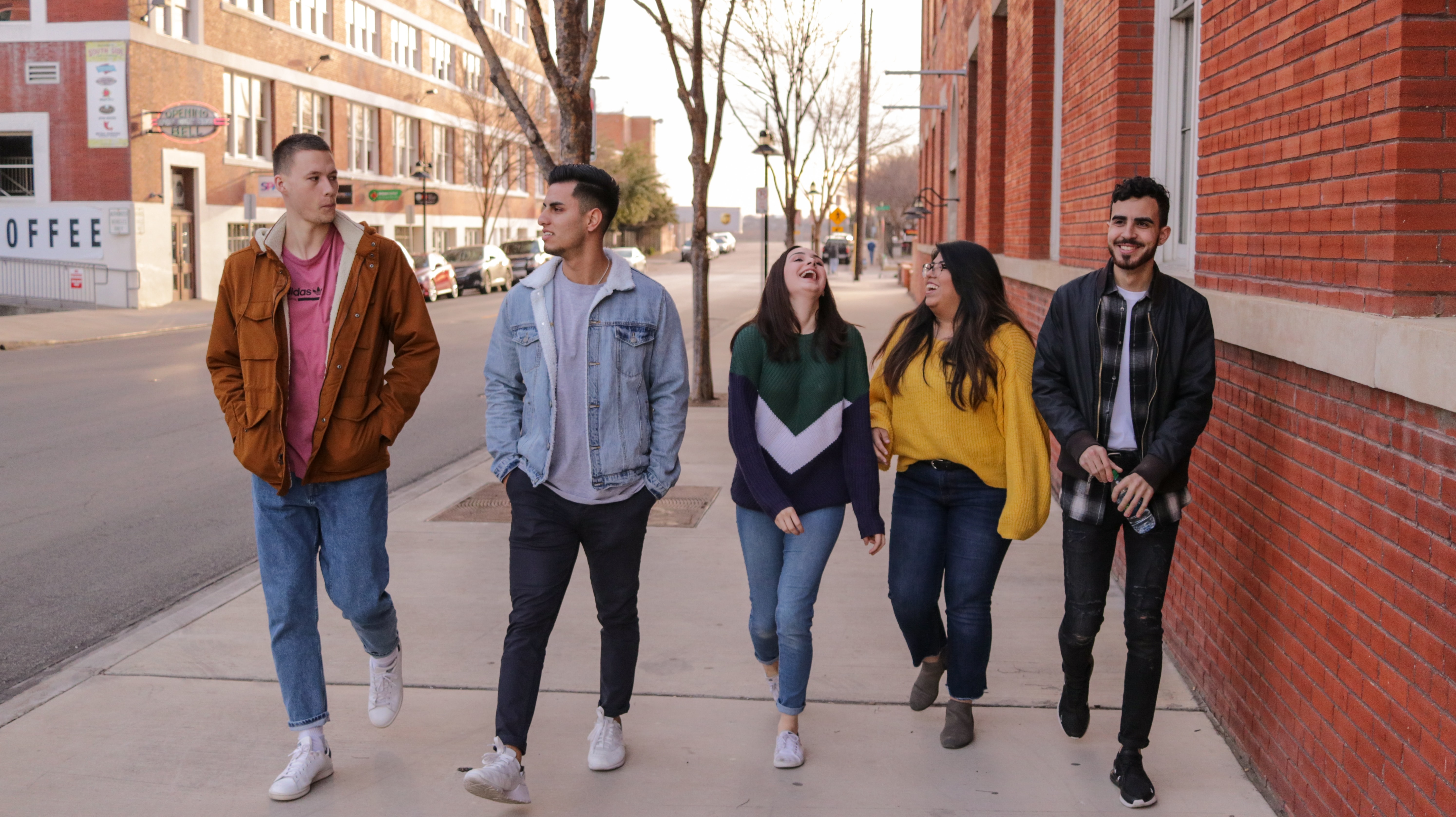 A group of people walking down a sidewalk and laughing