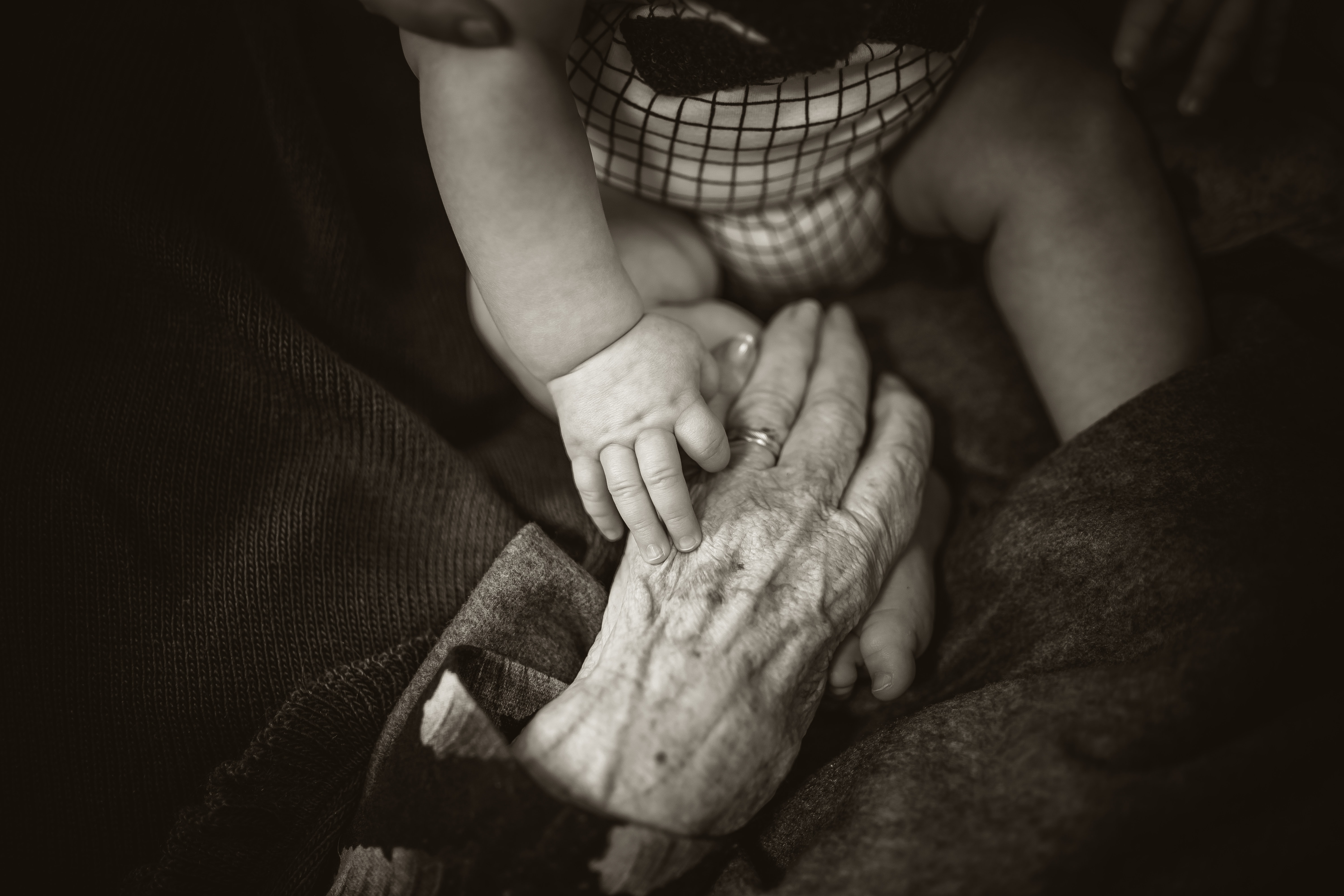 Elderly hand holding a baby