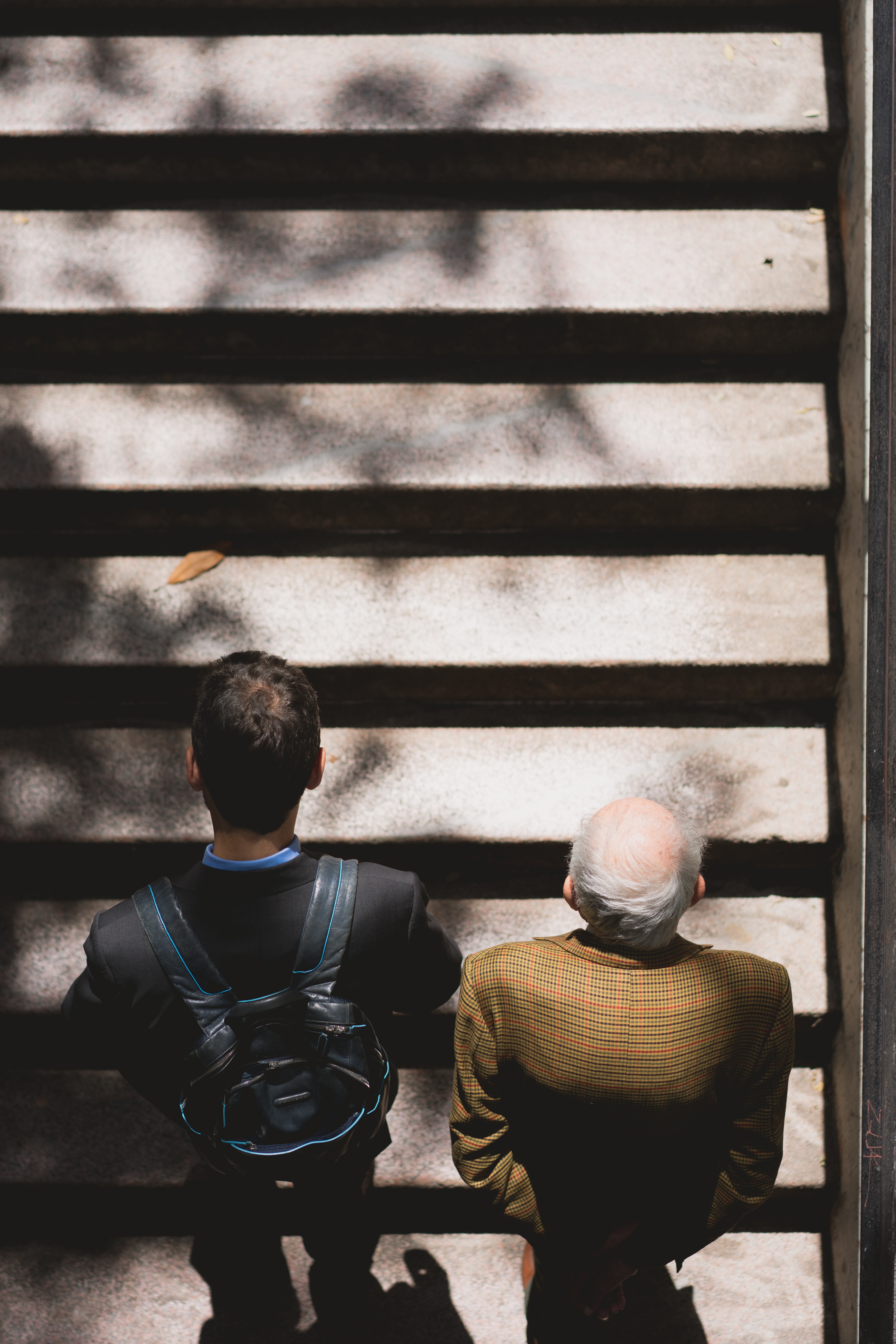 Photo of a young man and an elderly man climbing stairs
