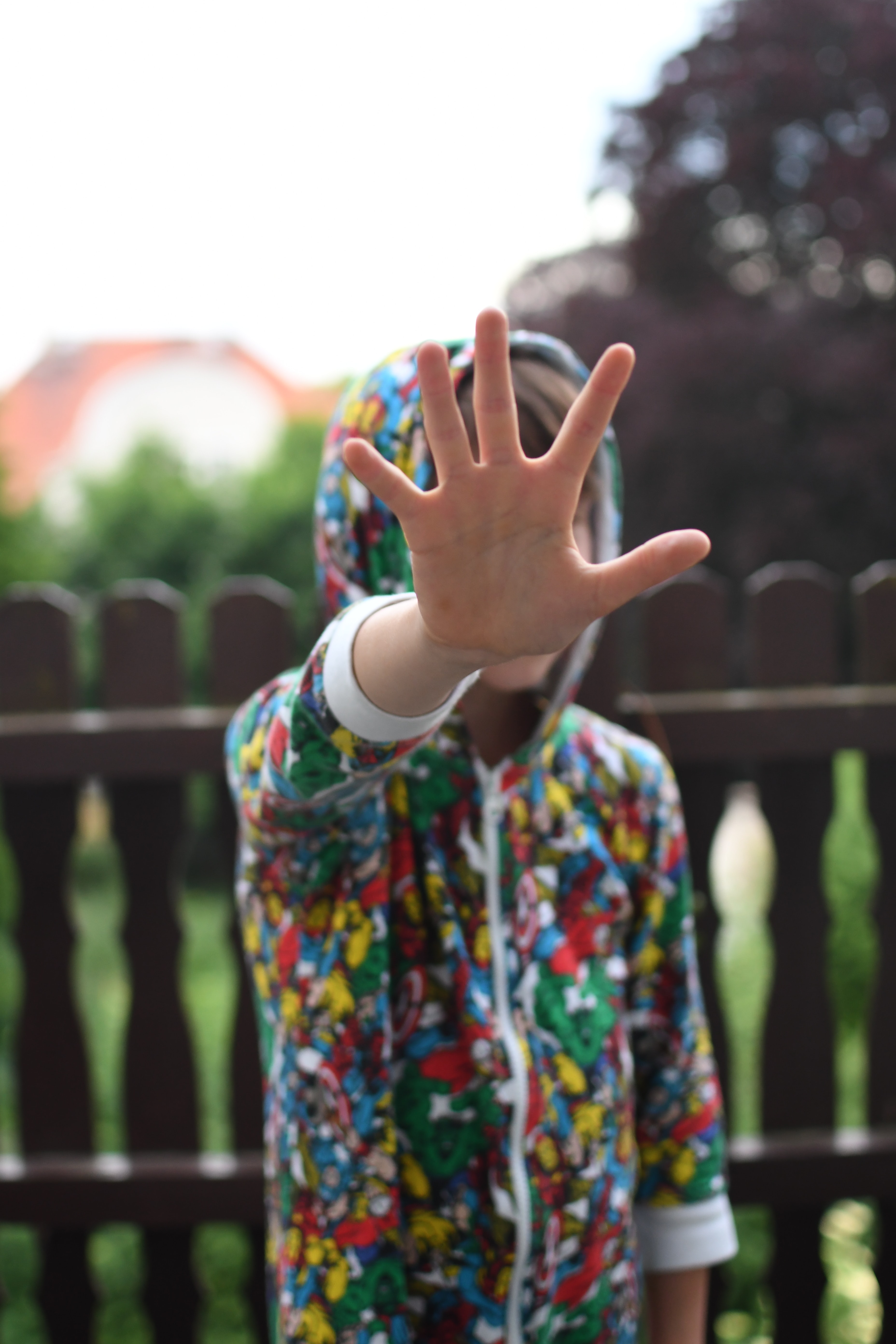 A person wearing a colorful hoodie holding hand out in a stopping gesture
