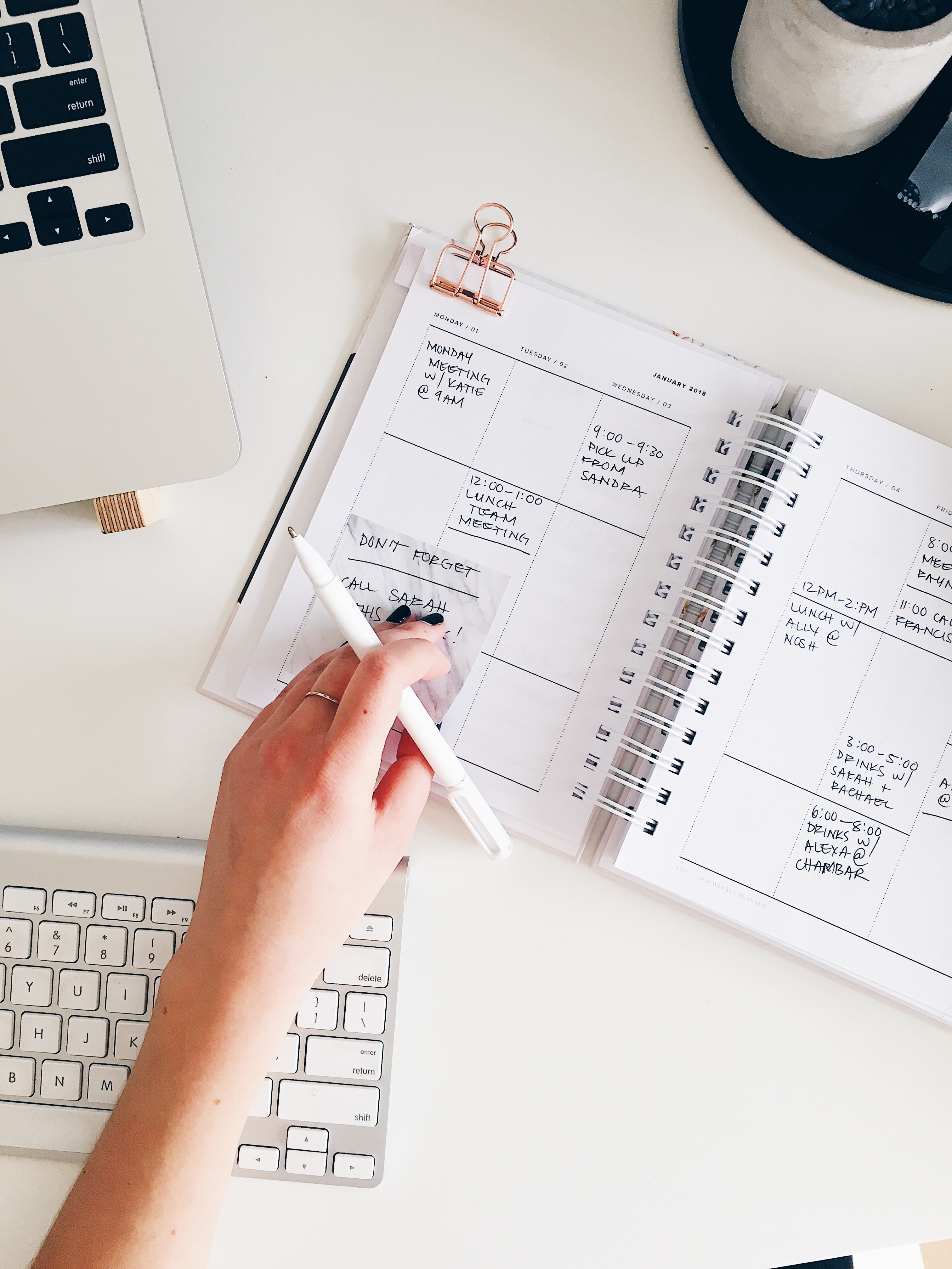 A person holding a pen while reviewing their planner