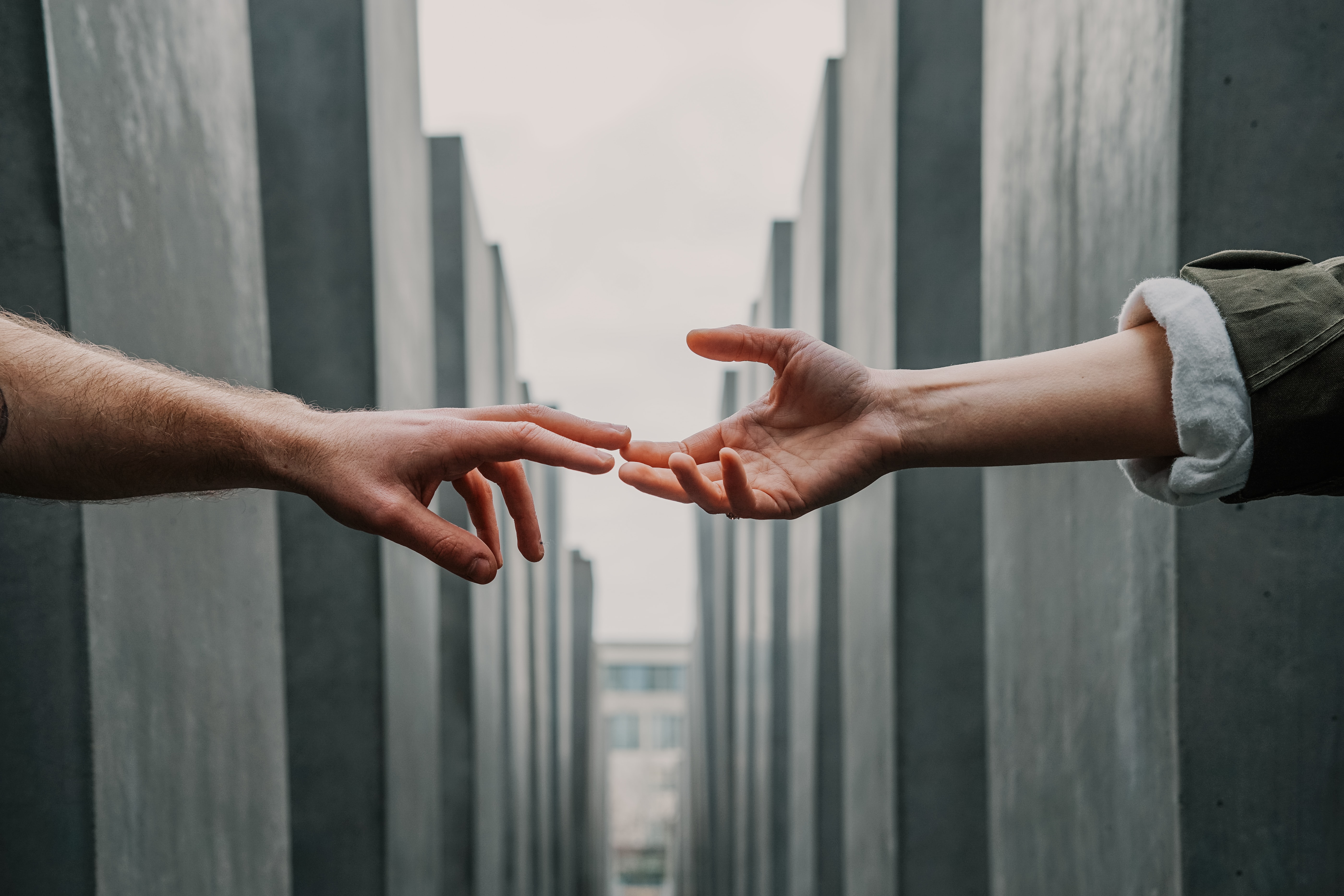 two people reaching out their hands to each other across a walkway