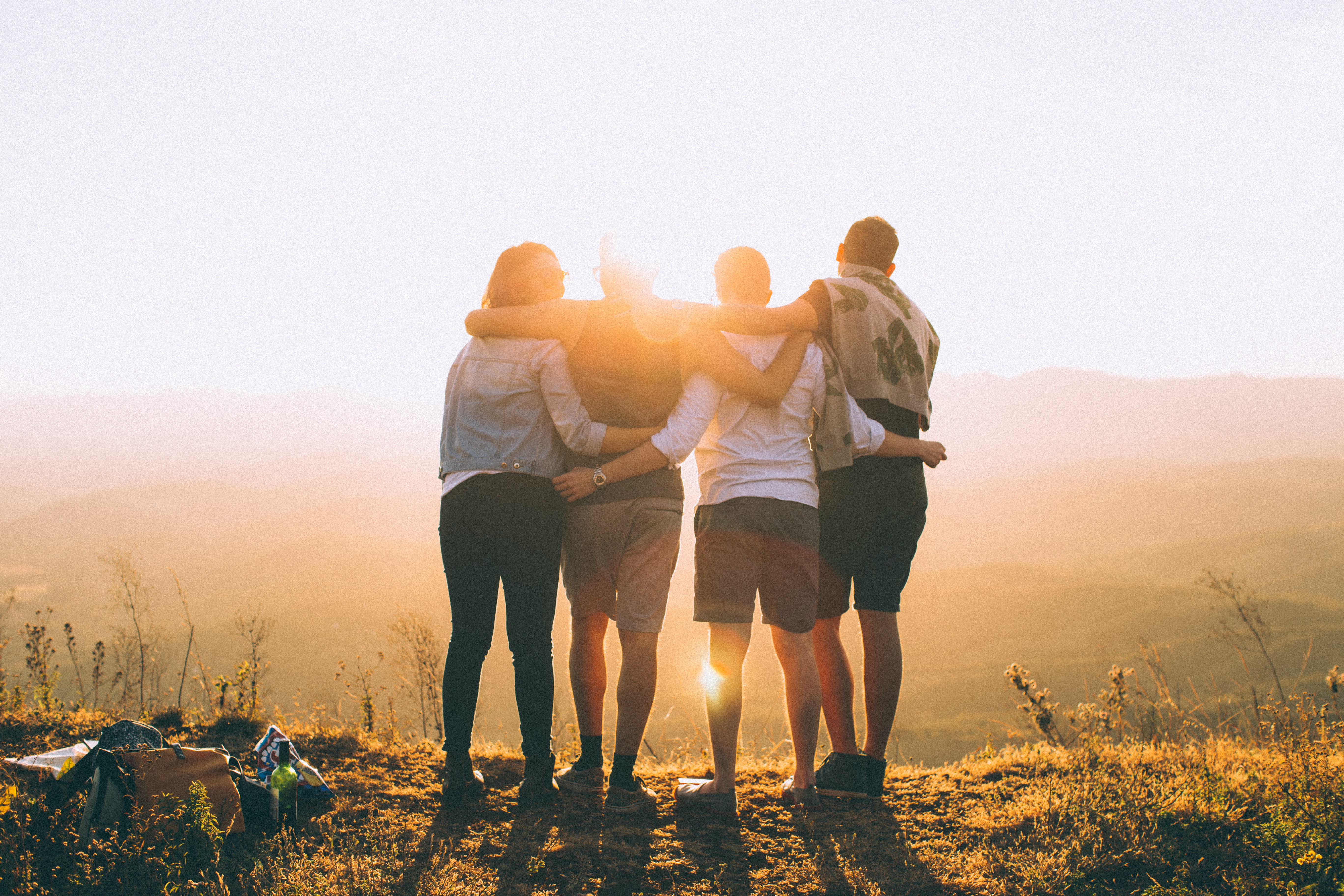 Four friends overlooking a valley at sunset